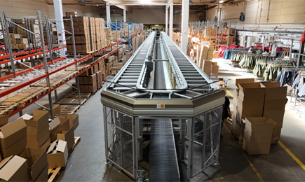 Automated sorting system in the middle of a warehouse surrounded by packaging boxes.